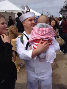 Sailor home from deployment holds baby.
